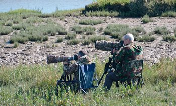 Two men wearing camouflage photographing nature